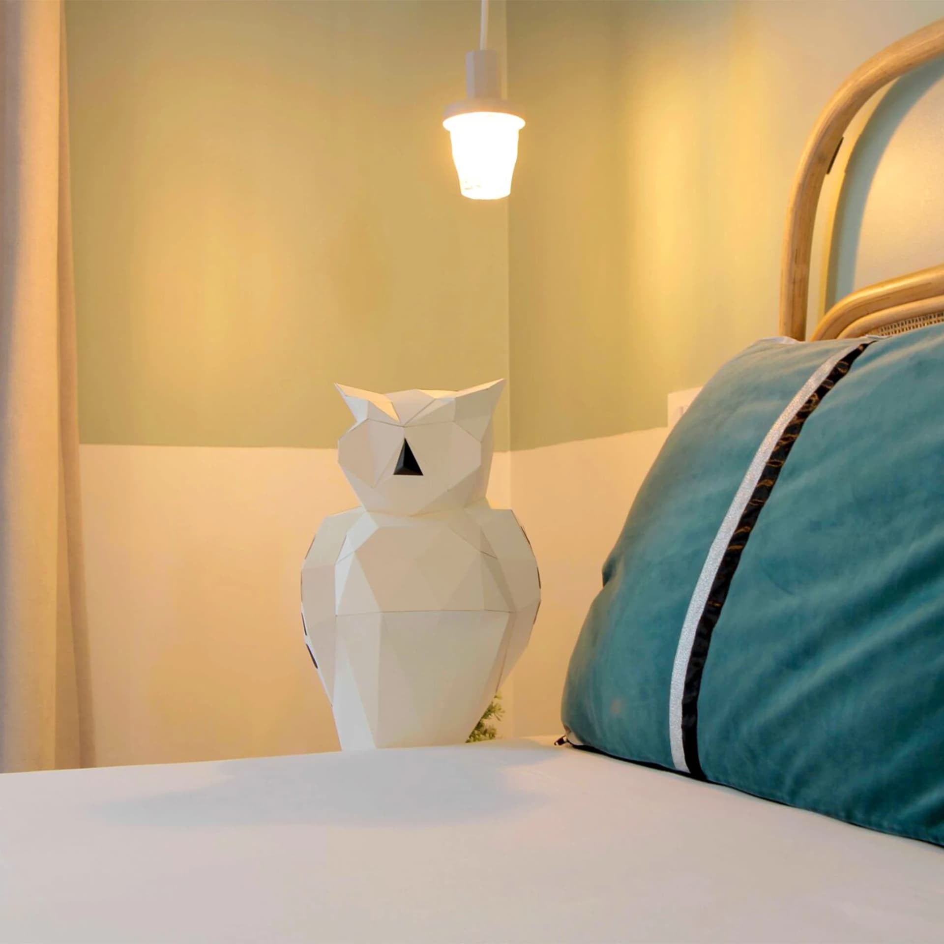 Décoration origami 3D en papier d'hibou blanc mis en situation au bord d'un lit