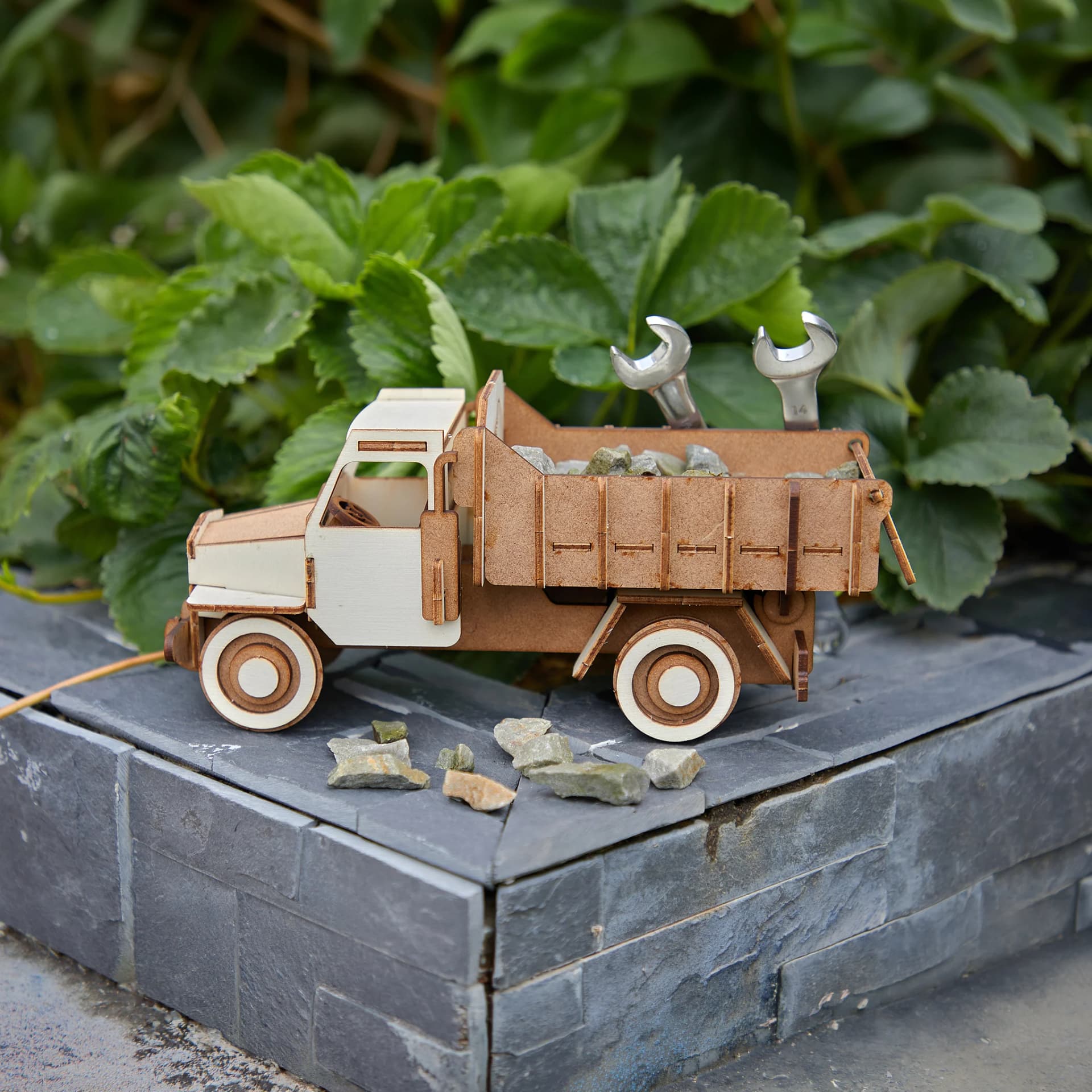 décoration en bois de camion benne posé sur un muret gris devant une plante