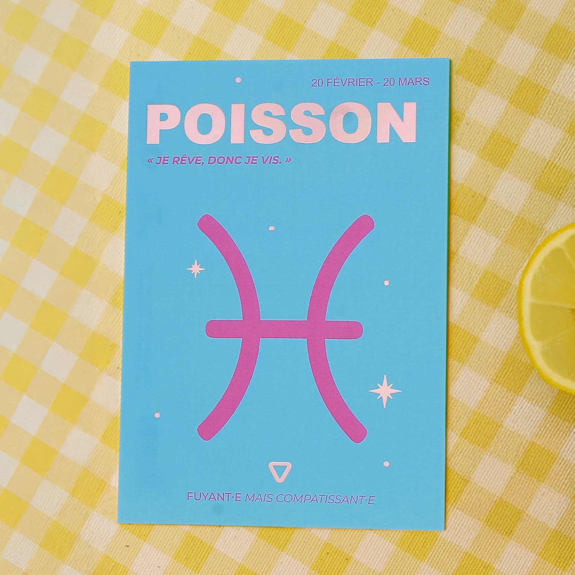 Papeterie cartes postales Astro Poisson posée sur une nappe quadrillée jaune avec un citron