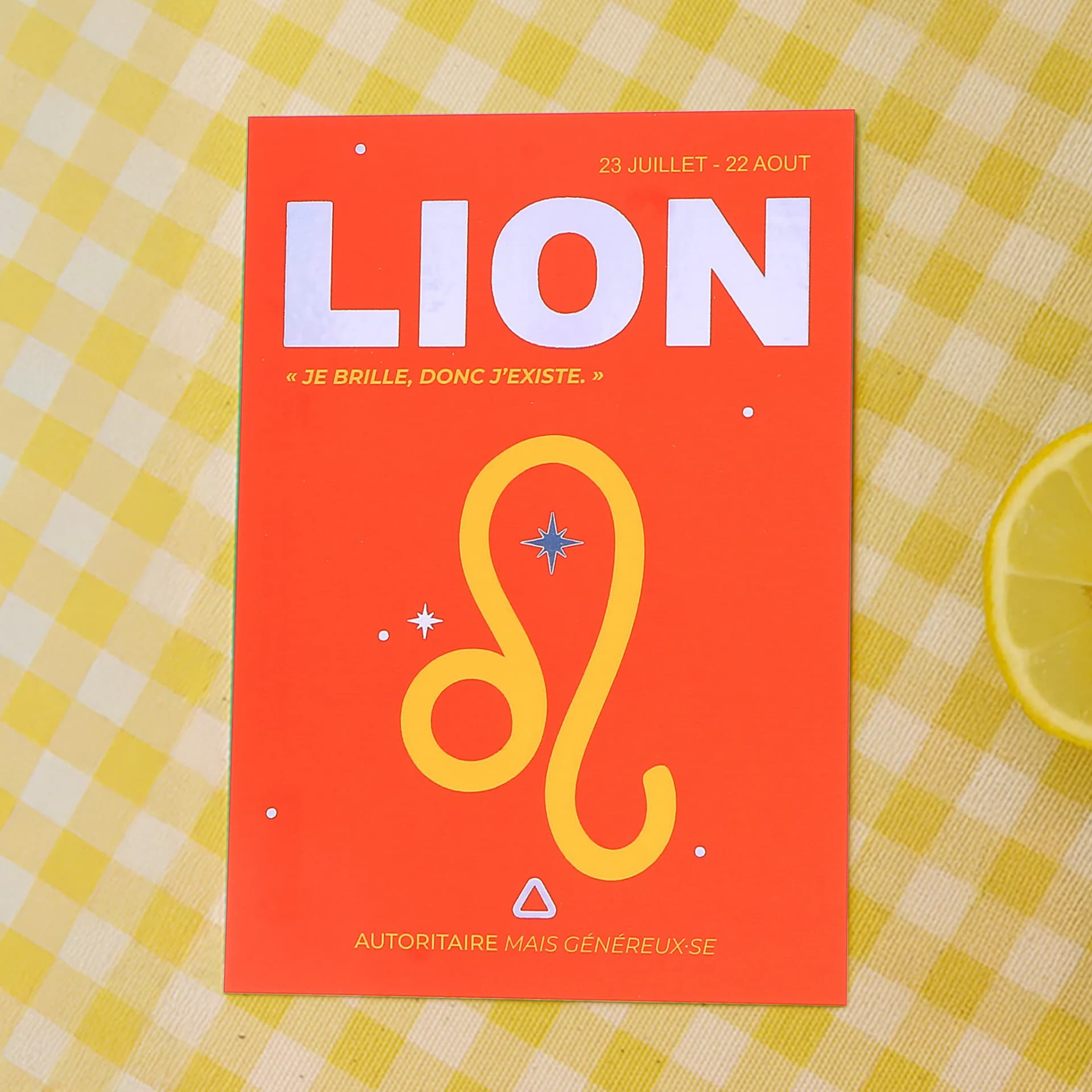 Papeterie cartes postales Astro Lion posée sur une nappe quadrillée jaune avec un citron