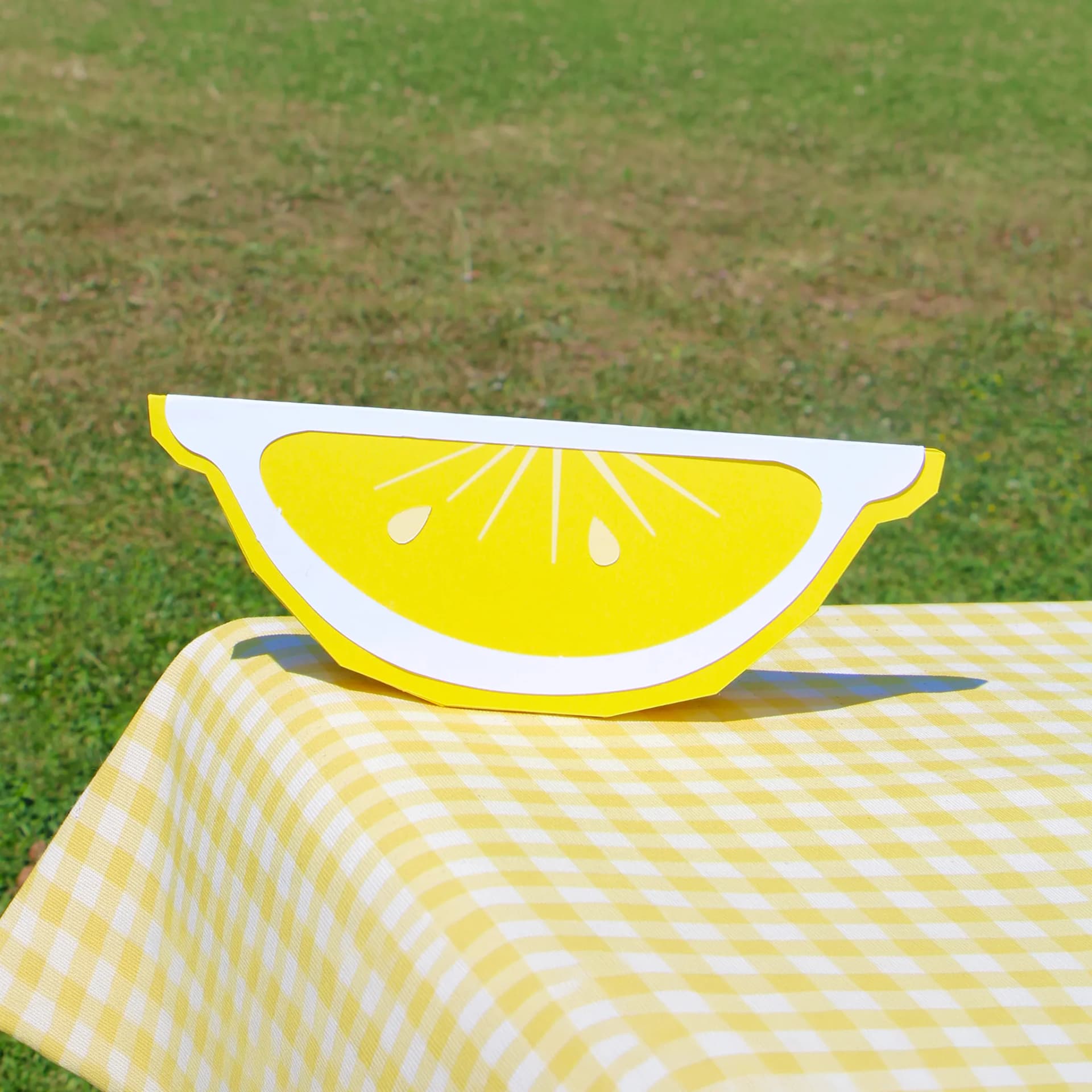 Décoration origami citron en papier sur une nappe jaune sur l'herbe