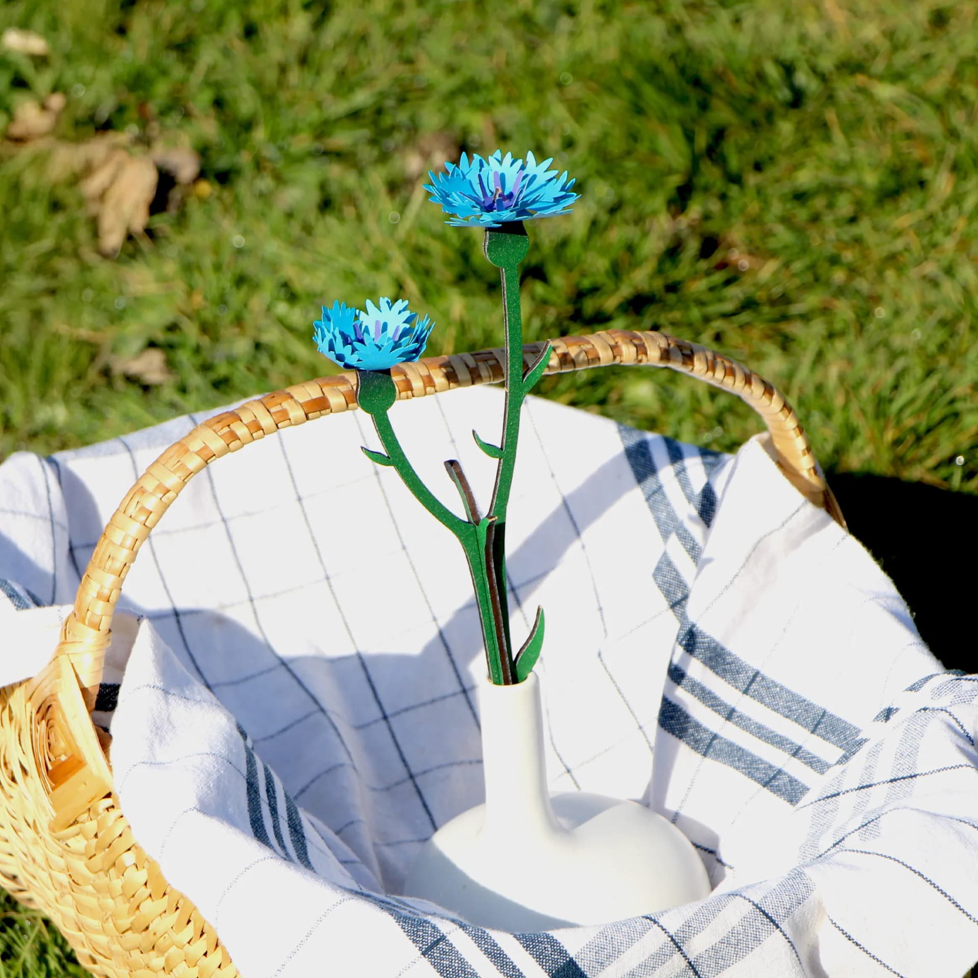 Décoration construction florale BLEUET dans un vase dans un panier sur l'herbe