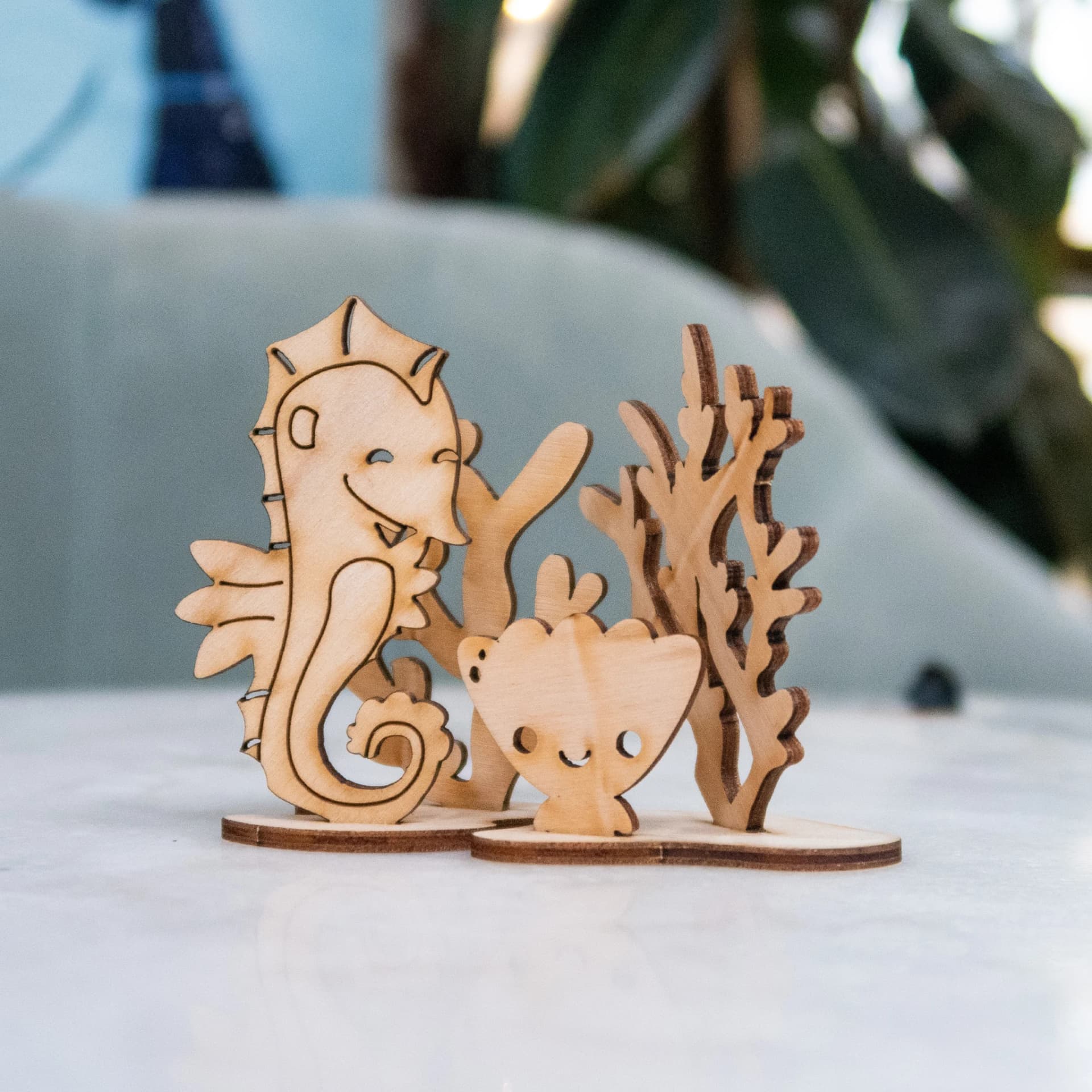 Décoration les p'tits bidules en bois Hippocampe posé sur un fond bleu devant des plantes