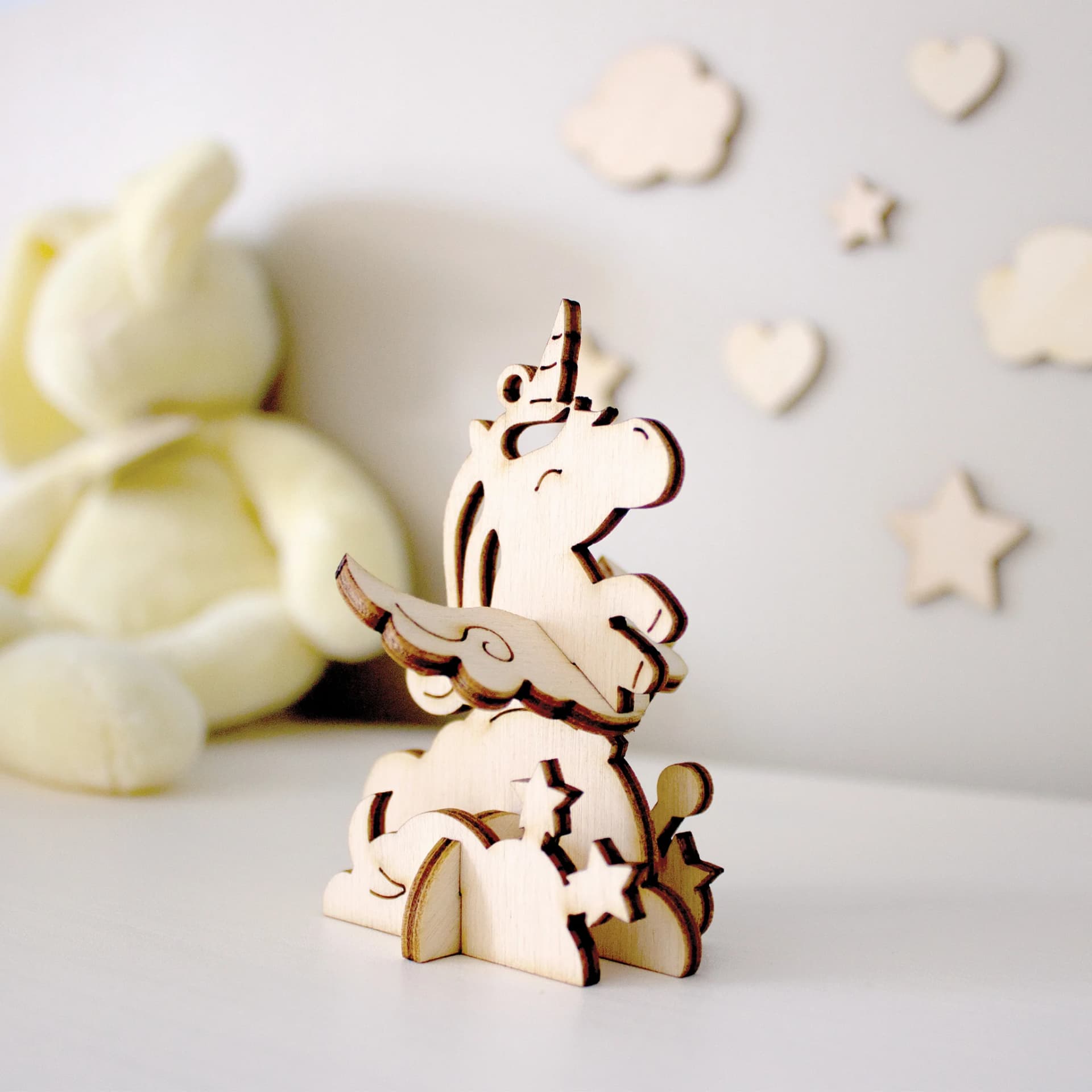 Décoration les p'tits bidules en bois Licorne nuages posée devant une peluche et des petits objets en bois