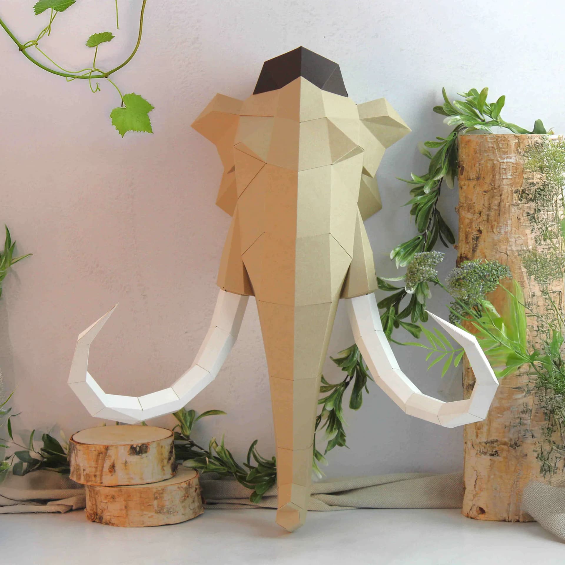 Décoration origami Mammouth en papier posé au mur à côté de plantes et de troncs