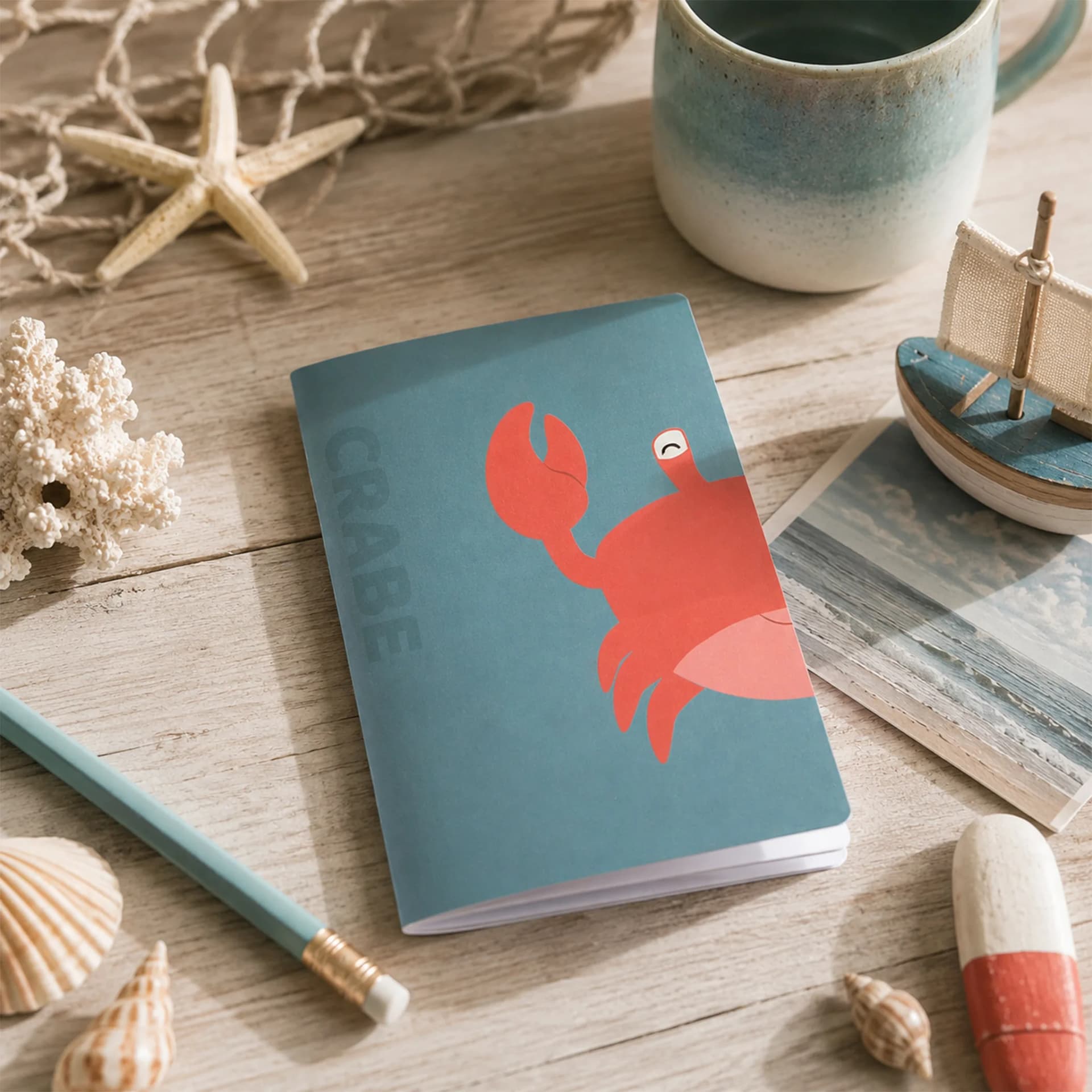 Mini Carnet ECCQ Crabe mis en situation, posé sur une table avec des éléments marins