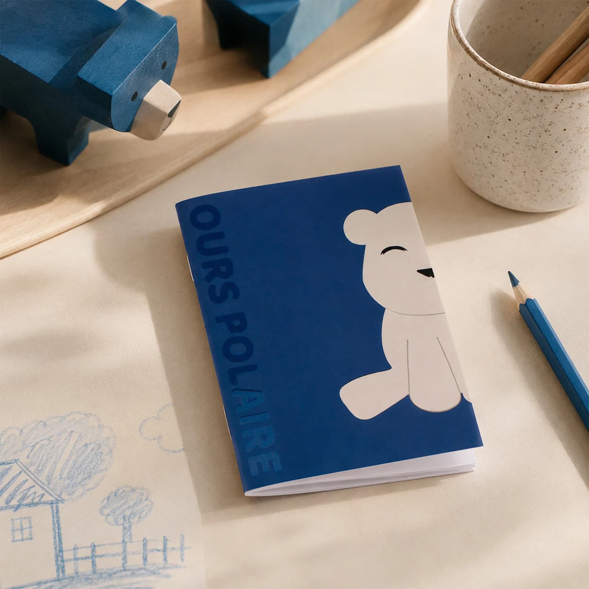 Mini Carnet ECCQ ours polaire mis en situation sur une feuille blanche avec un dessin et éléments bleu