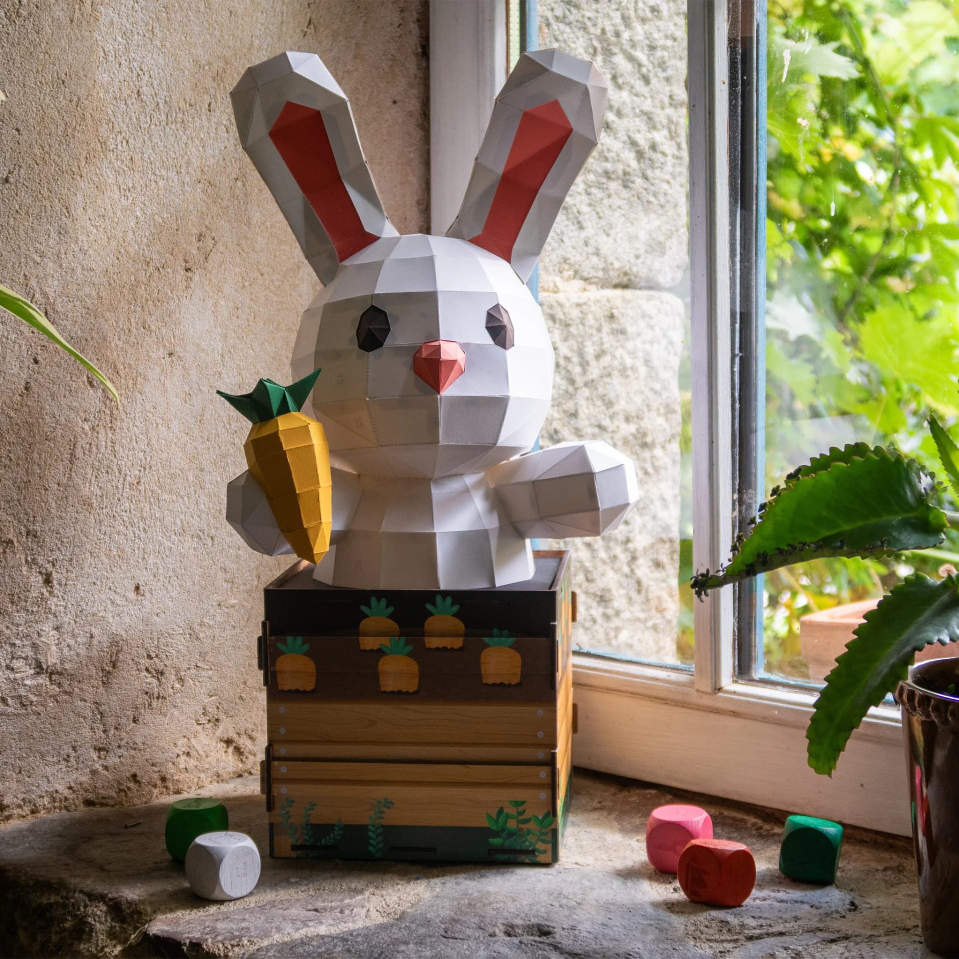 Décoration origami Petit Lapin Surprise sur une boîte à monter entouré de jouets