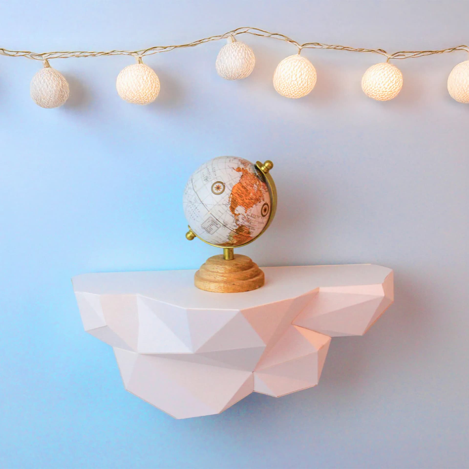Décoration origami Petit nuage irisé accroché sur un mur bleu avec un globe