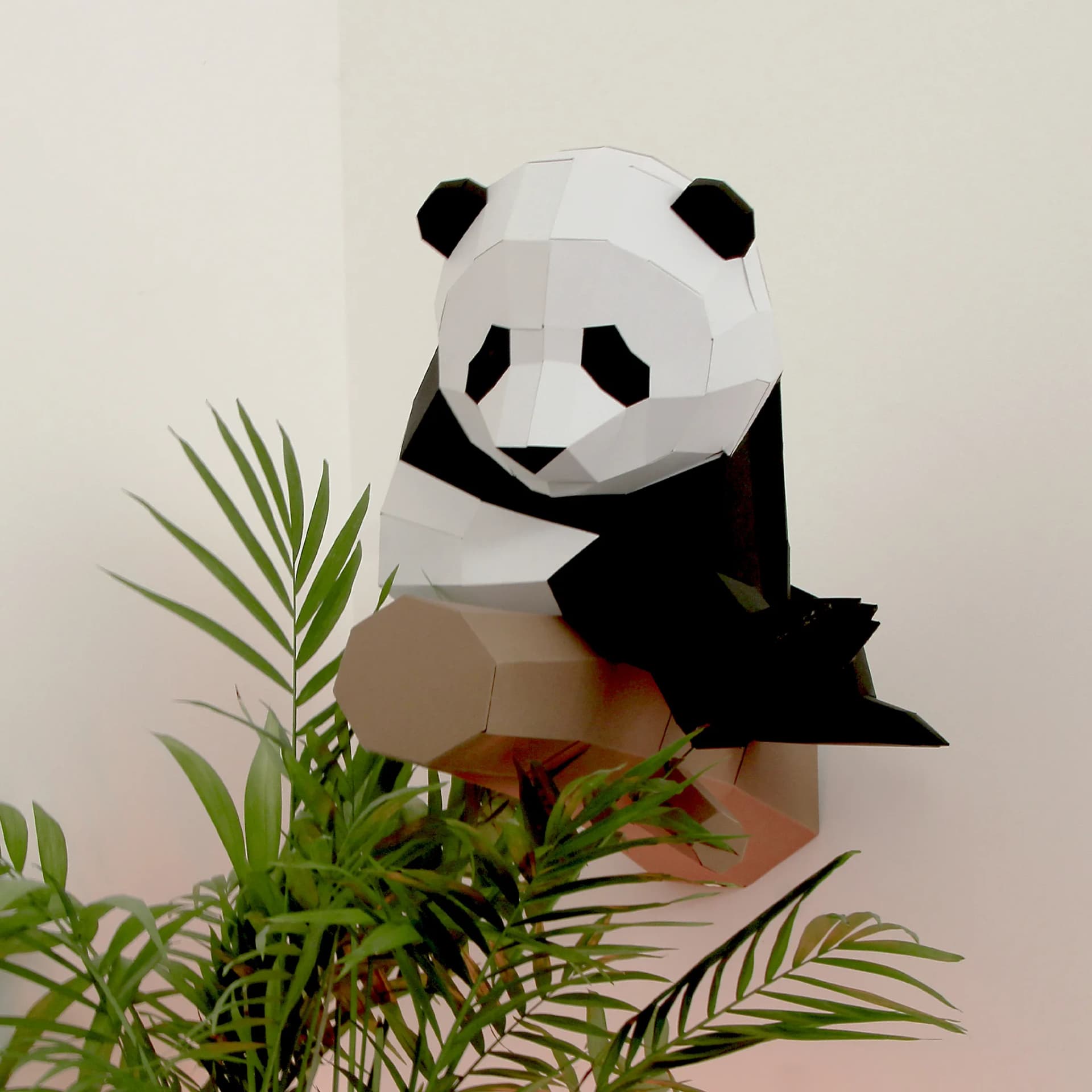Décoration origami Petit panda sur branche en papier blanc et noir accroché au mur au dessus de plantes