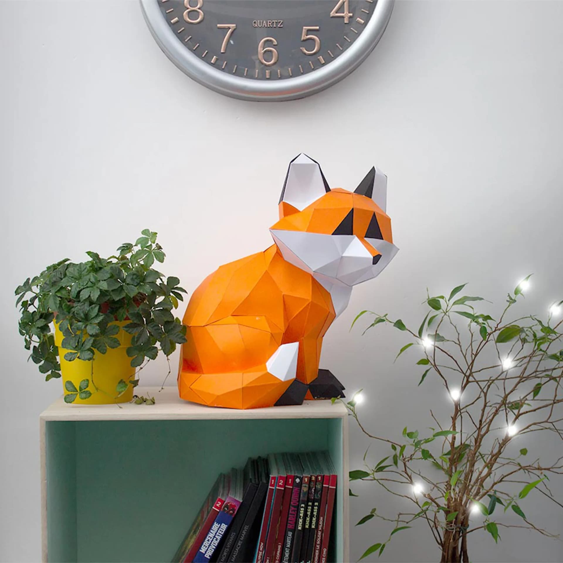 Décoration origami Petit renard assis en papier Orange posé sur un meuble à côté de plantes et de livres