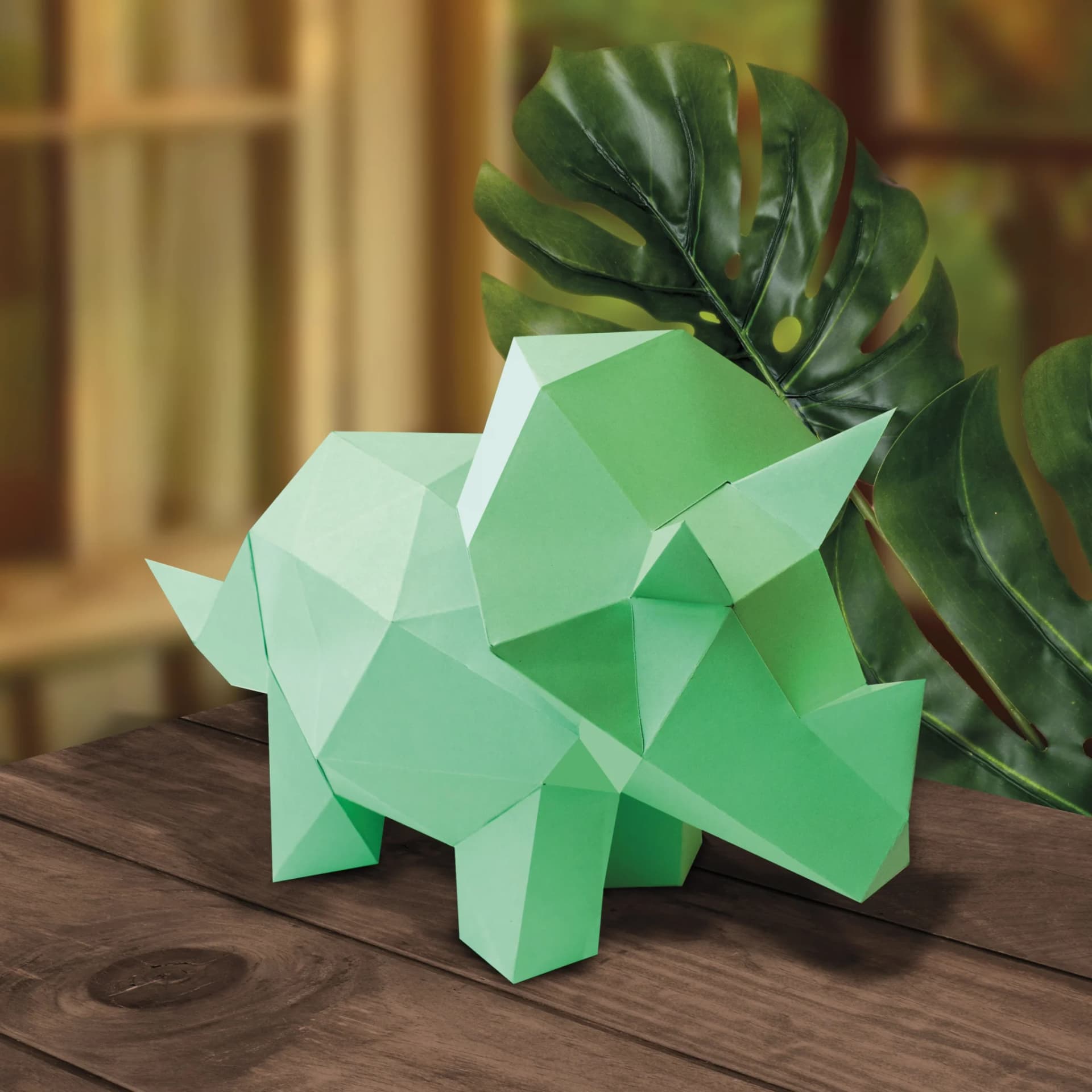 Décoration en papier trophée babies tricératops vert posé sur une table de salon en bois