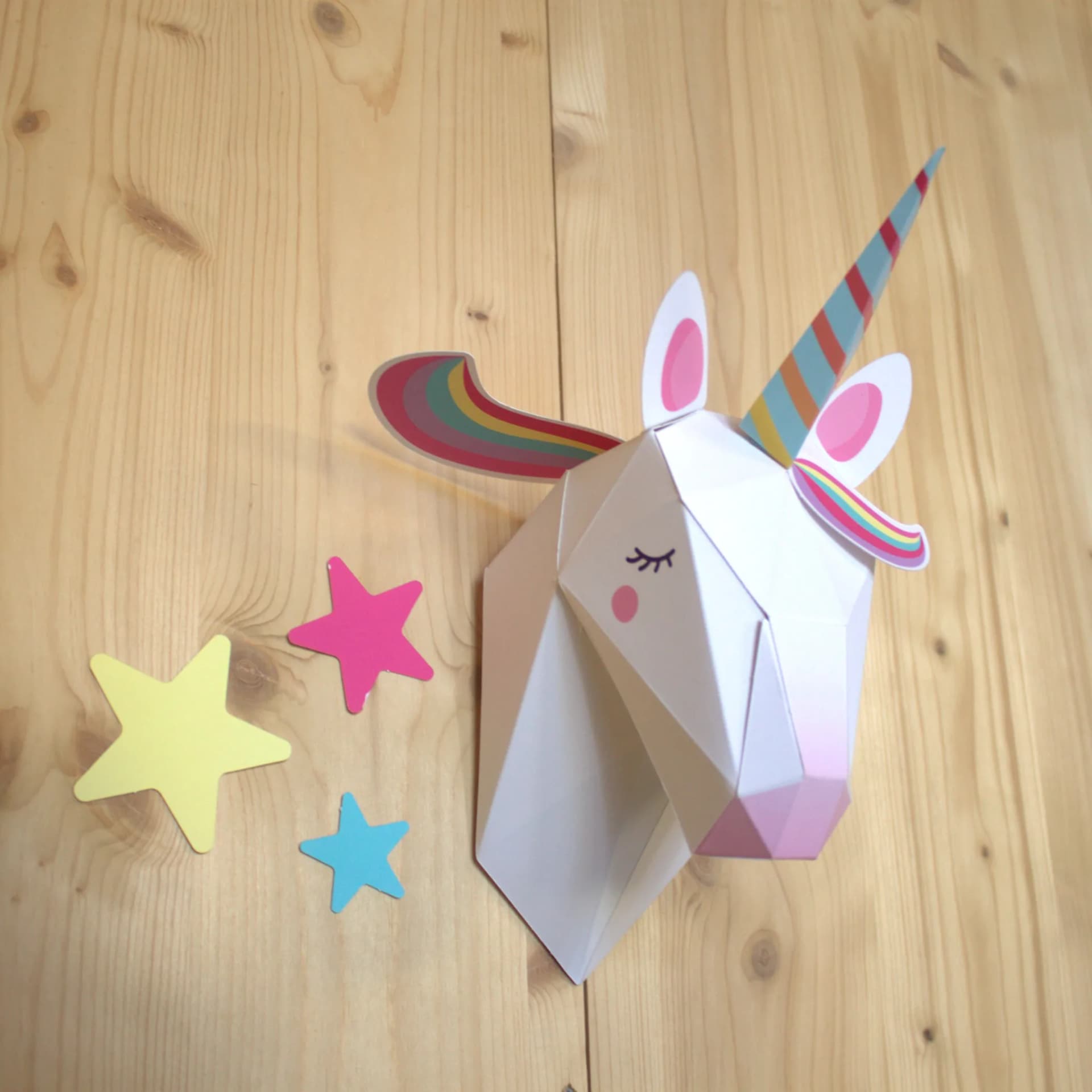 Décoration en papier trophée Easy Peasy licorne  dans une chambre d'enfant, accrochés au mur au dessus du lit