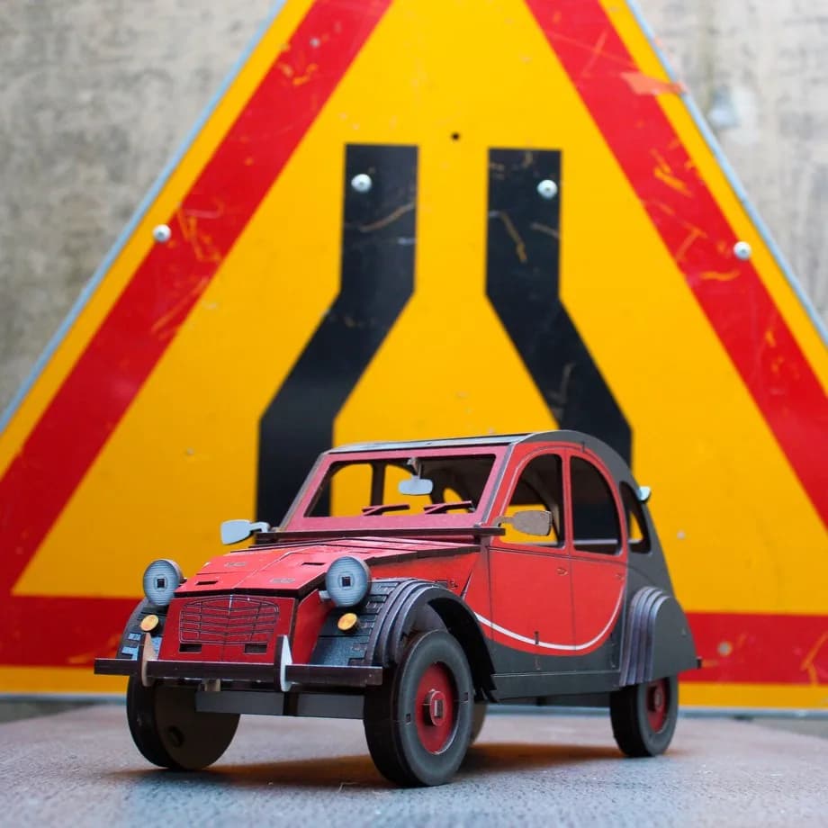 Décoration en bois voiture 2CV rouge posée sur un panneau de signalisation