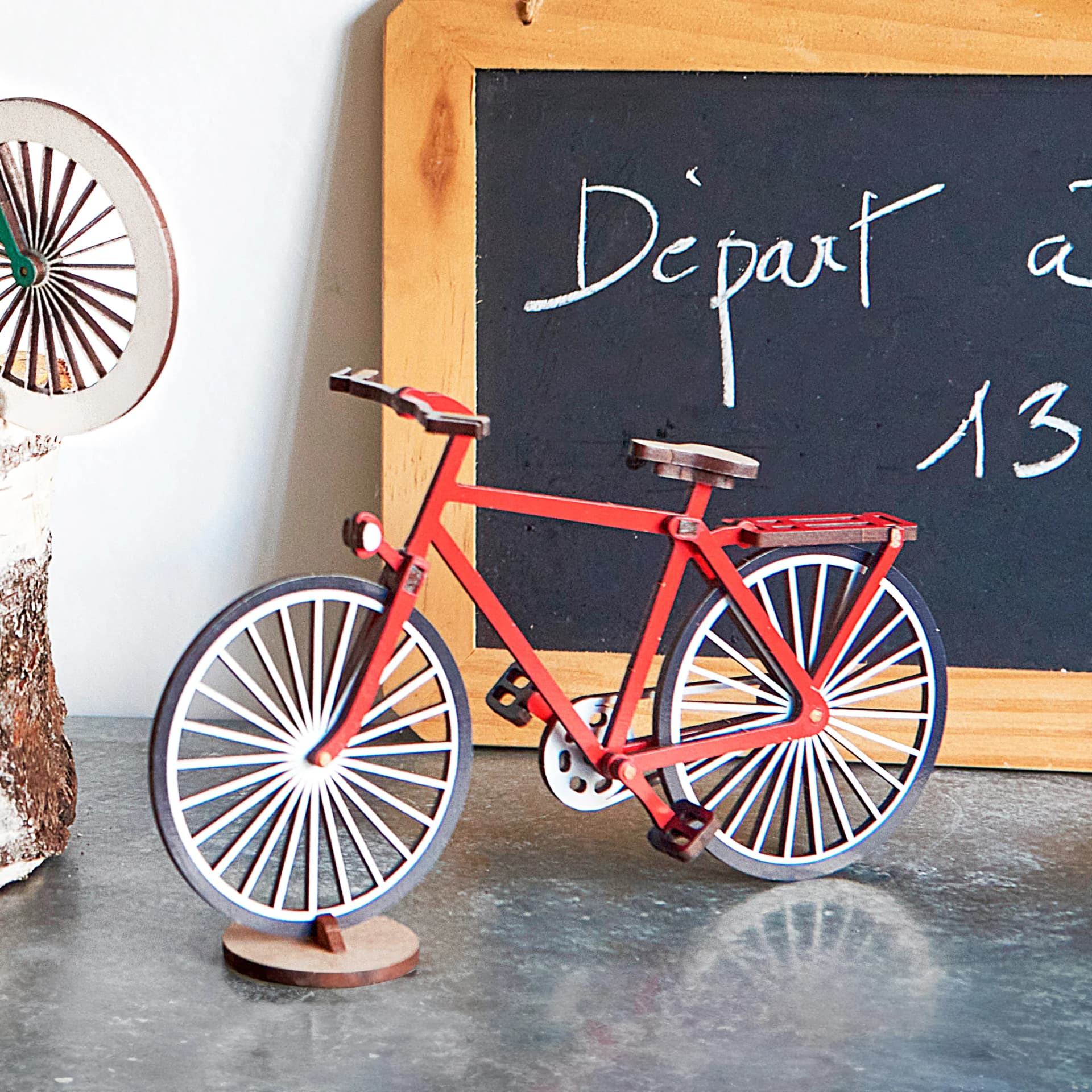 Maquette d'un vélo en bois rouge posé sur une table d'un salon