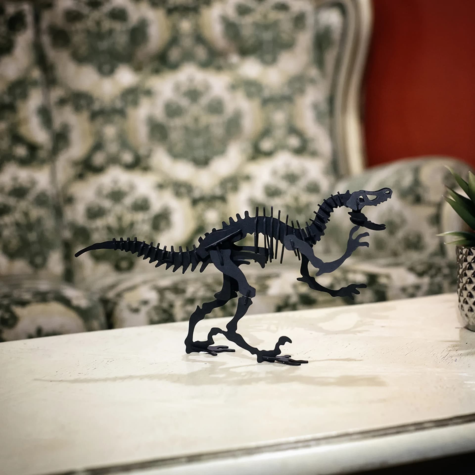 Vélociraptor en carton noir posé sur une table de salon en bois